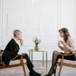 Two women engaged in a counseling session in a bright, modern loft setting.