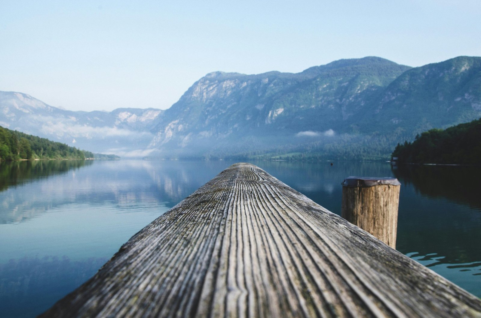 Serene view of a mountain lake from a wooden dock in Radovljica, Slovenia.